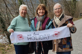 drei Damen halten ein Schild mit der Aufschrift "We love holiday"