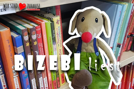 Das Stadtbibliotheksmaskottchen Bizebi sitzt im Bücherregal der Stadtbibliothek.