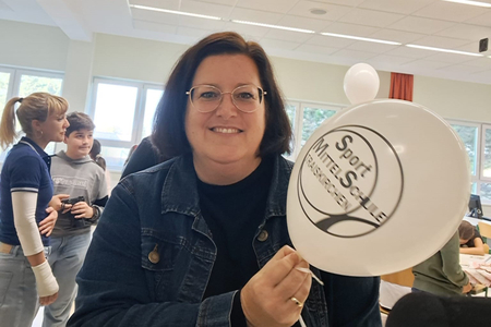 Bgm.in Divoky hält einen Luftballon der SPort Mittelschule