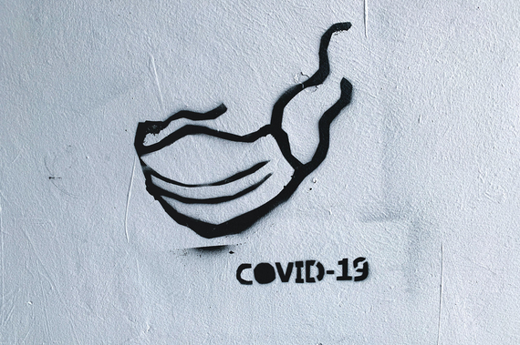 Weiße Wand mit gesprayter Covid19 Schutzmaske.