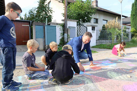 Bgm. Babler bemalt zusammen mit Schulkindern die Straße