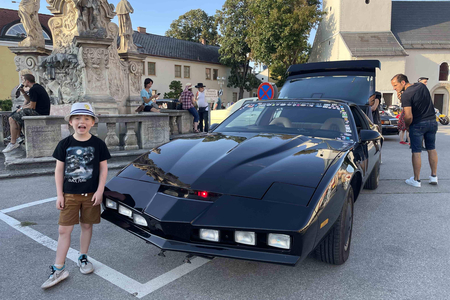 Ein Kind das vor dem Auto KITT steht