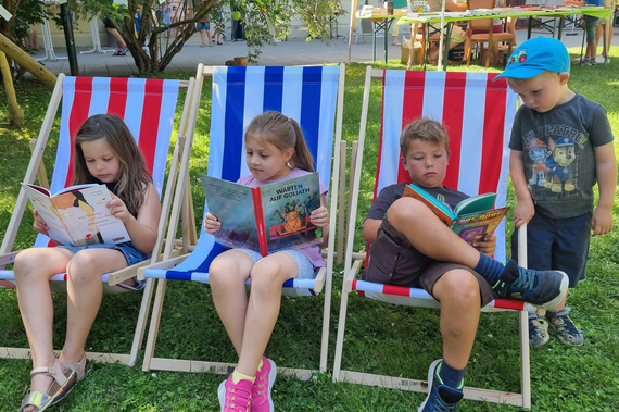 3 Kinder lesen in Liegestühlen ein Buch
